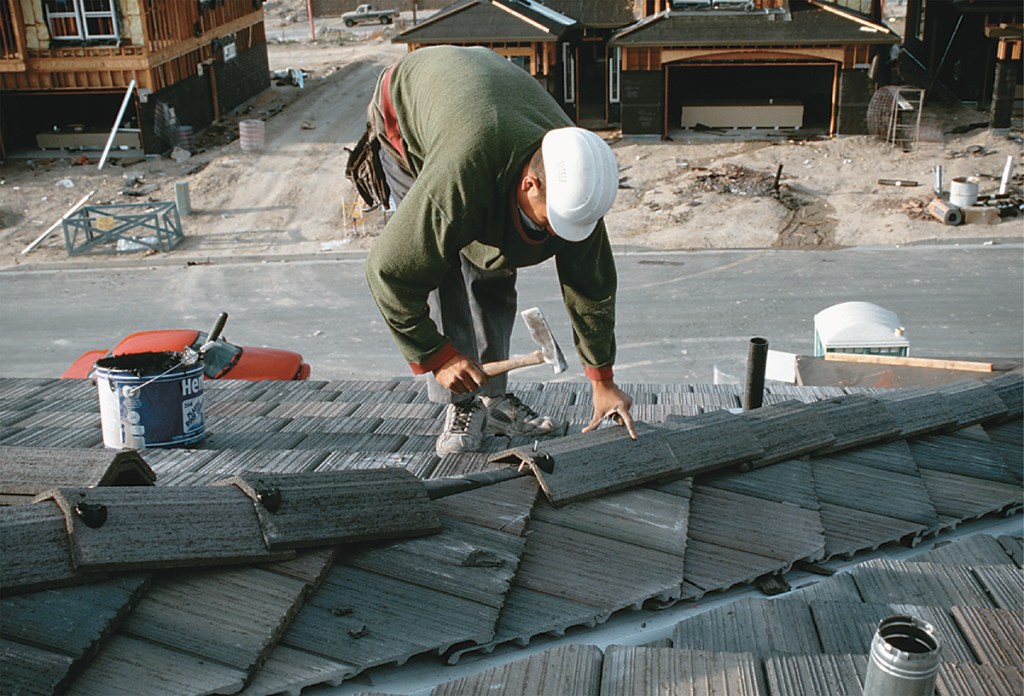 Roofer positioning tiles on pitched roof